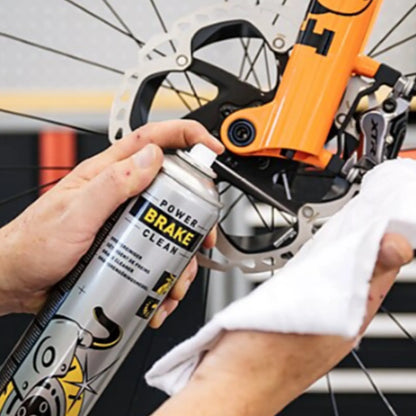 Person cleaning a bicycle brake system with a can of Motorex Power Brake Clean Spray 750ml.