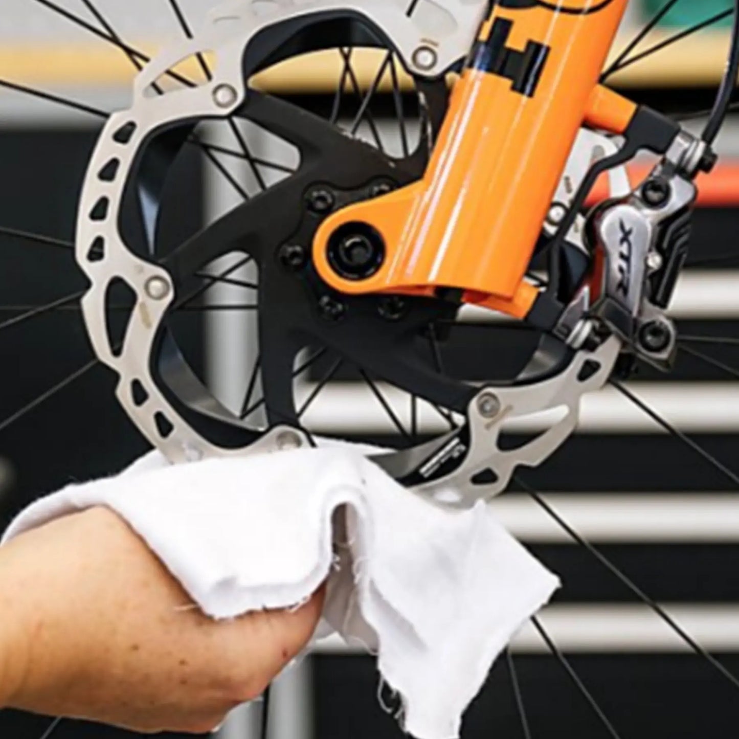 Person cleaning a bicycle brake system with a can of Motorex Power Brake Clean Spray 750ml.