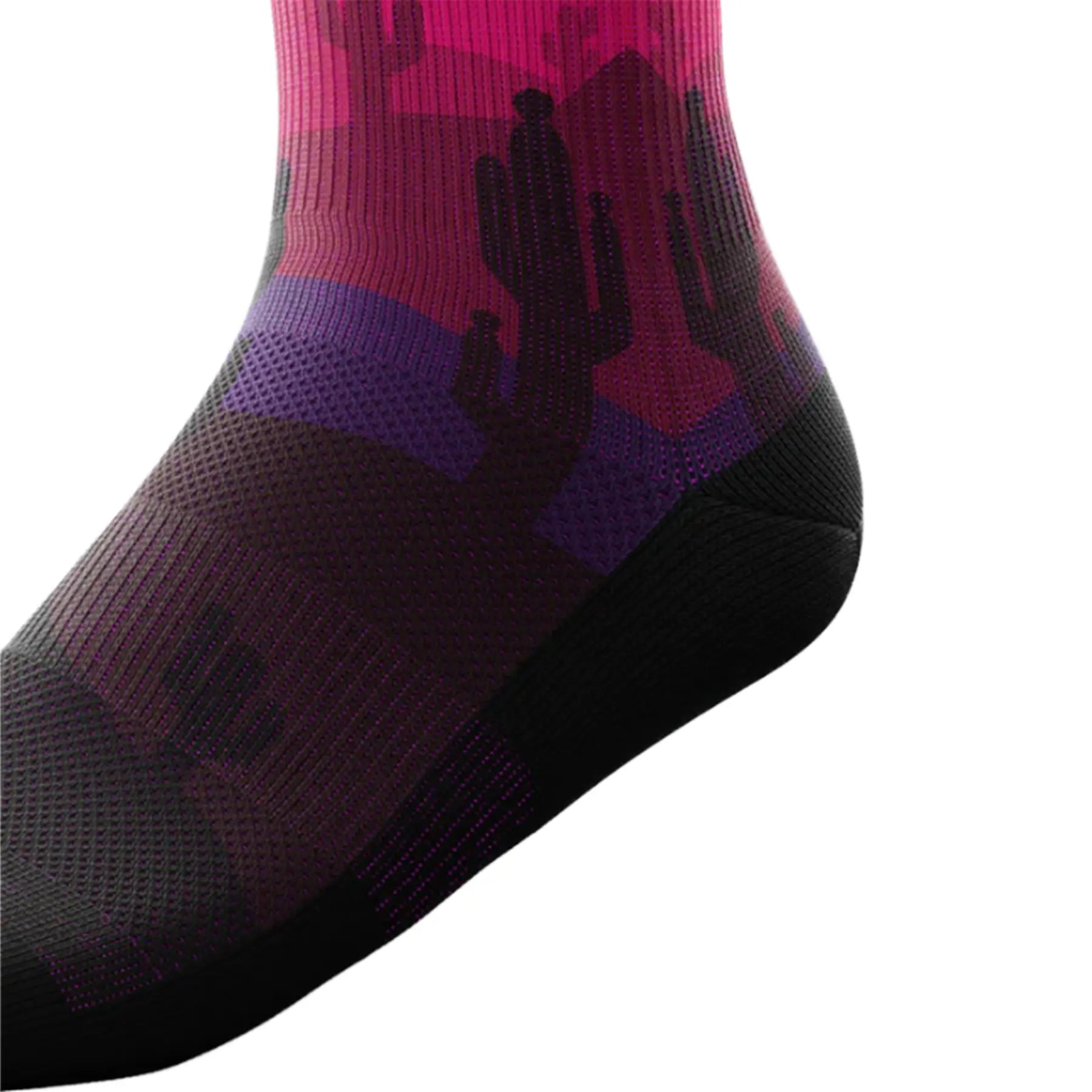 The Outway Dune Crew Socks feature a desert landscape with cactus in pinks, purples and orange, with a blue sky and a yellow sun, while the bottom of the sock is black.