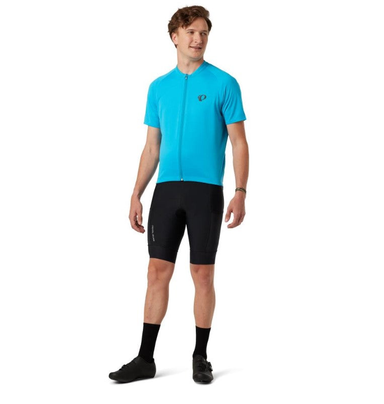 Man wearing a blue cycling jersey and black Pearl Izumi Expedition bib shorts on a white background.