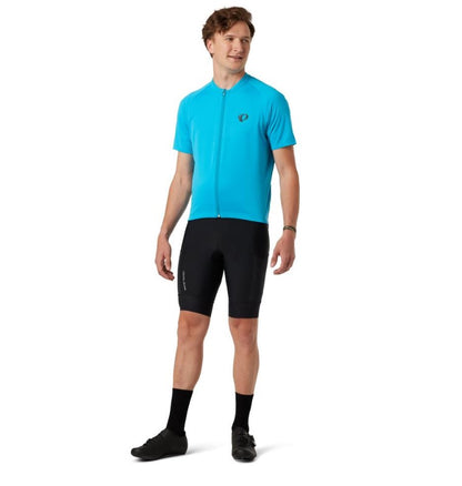 Man wearing a blue cycling jersey and black Pearl Izumi Expedition bib shorts on a white background.