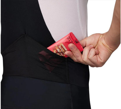 Person putting a red snack packet into the back pocket of a Pearl Izumi Expedition cycling bib short. 