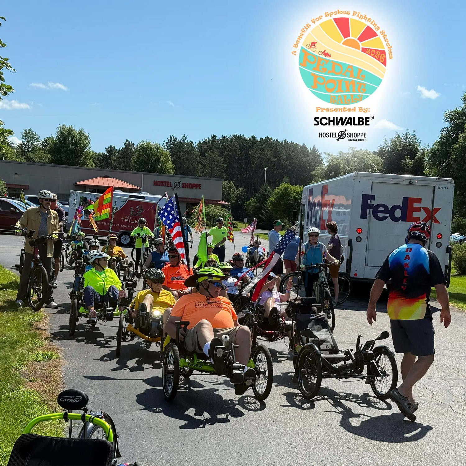 Group of people lining up to ride recumbent trikes at the Pedal Point Rally in front of the Hostel Shoppe.