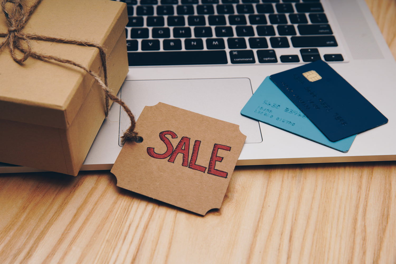A brown box sits by a laptop with a sale tag on it. Two credit cards sit on the laptop.