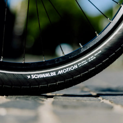 Closeup of the black Schwalbe Motion Big Apple Tire on a bike outside.