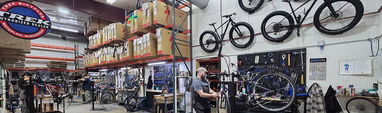 Bicycle repair shop with bikes on walls and shelves, tools, and equipment.