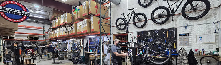 Bicycle repair shop with bikes on walls and shelves, tools, and equipment.