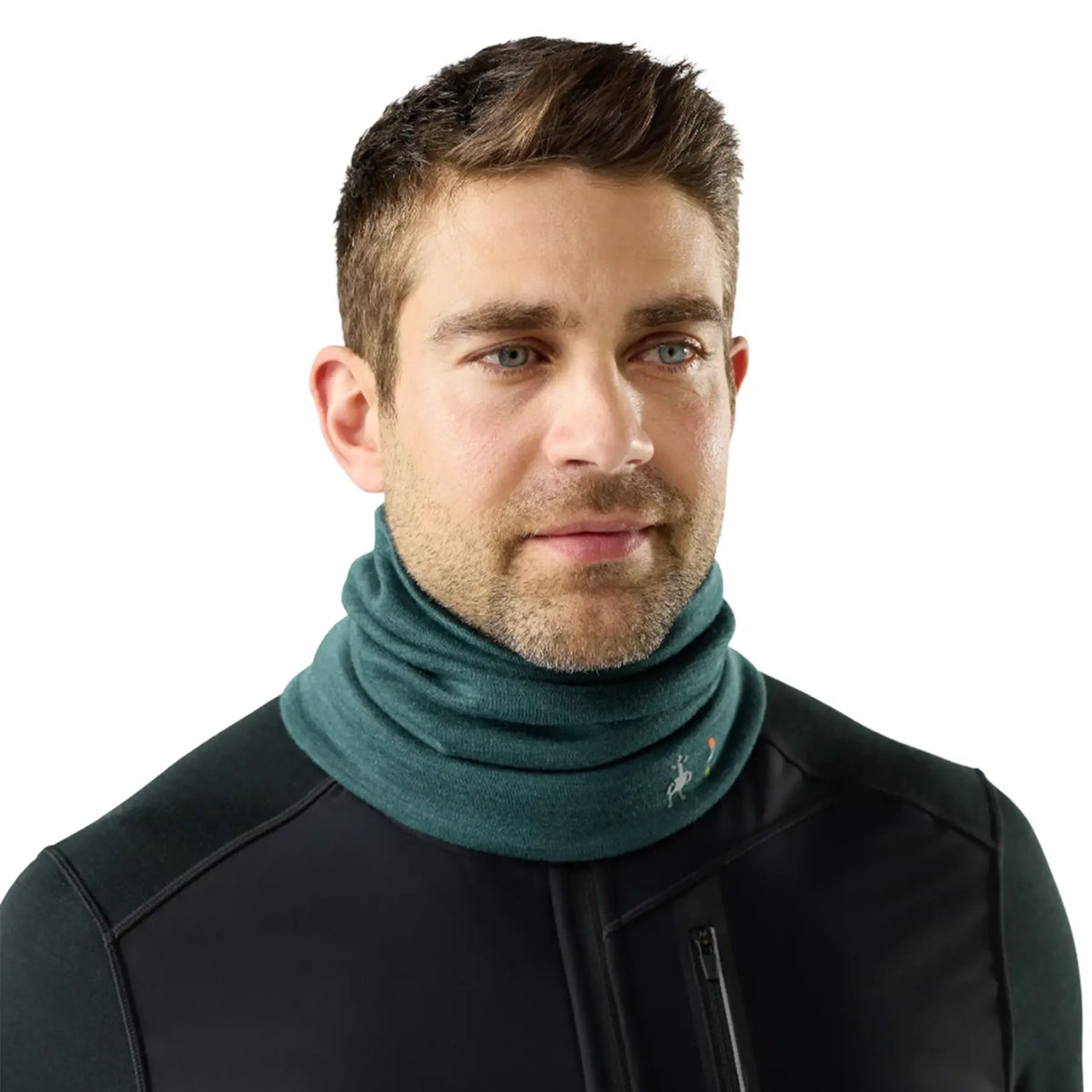 A man wearing a Smartwool Thermal Merino Reversible Neck Gaiter in Dark 
Teal Heather and a black zippered jacket, photographed against a solid white background.