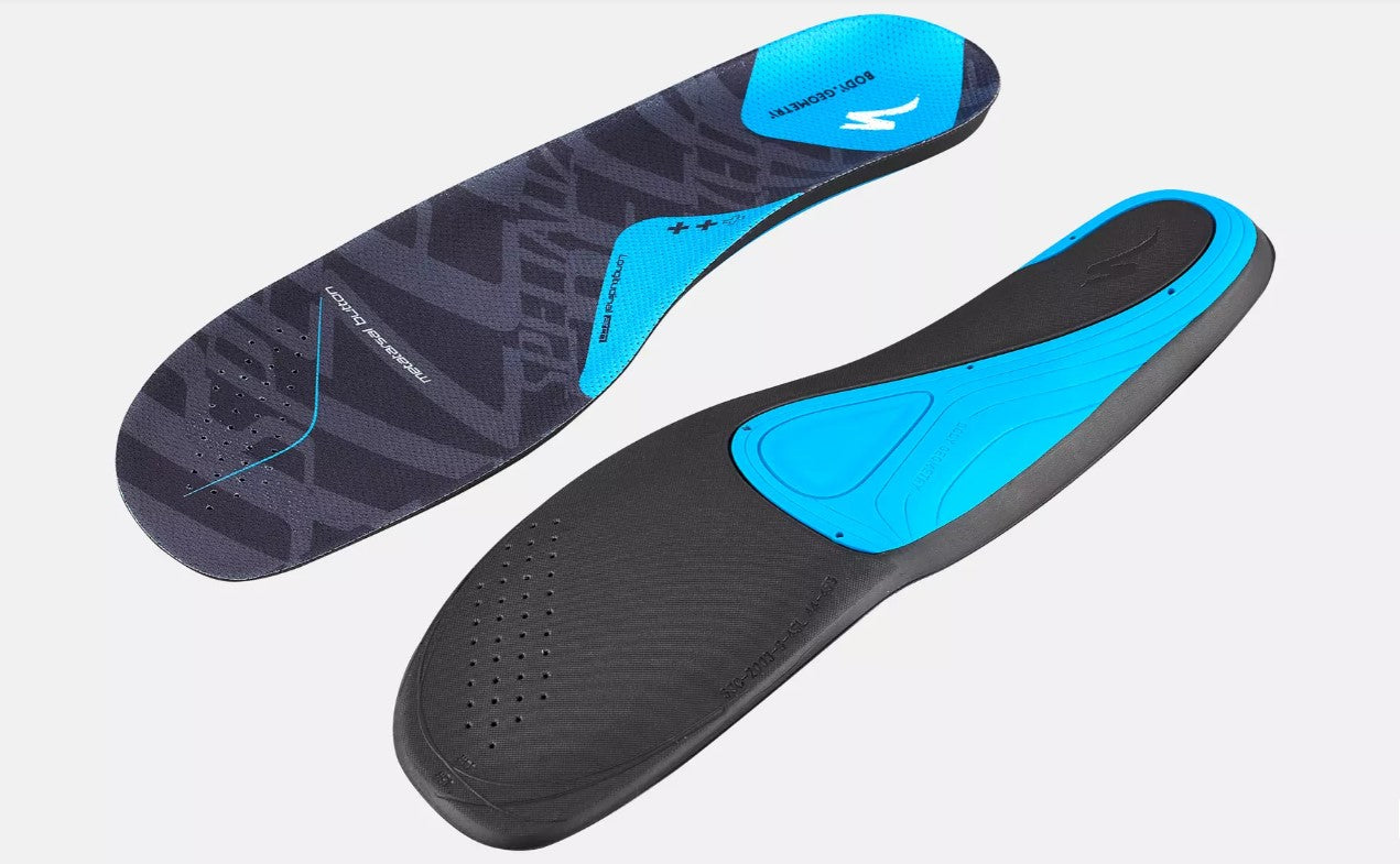 Black and blue Specialized Body Geometry SL footbed shoe insoles on a light gray background.