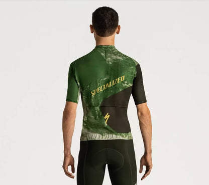 Back view of a man wearing a green and black Specialized Foundation short sleeve cycling jersey on a white background.