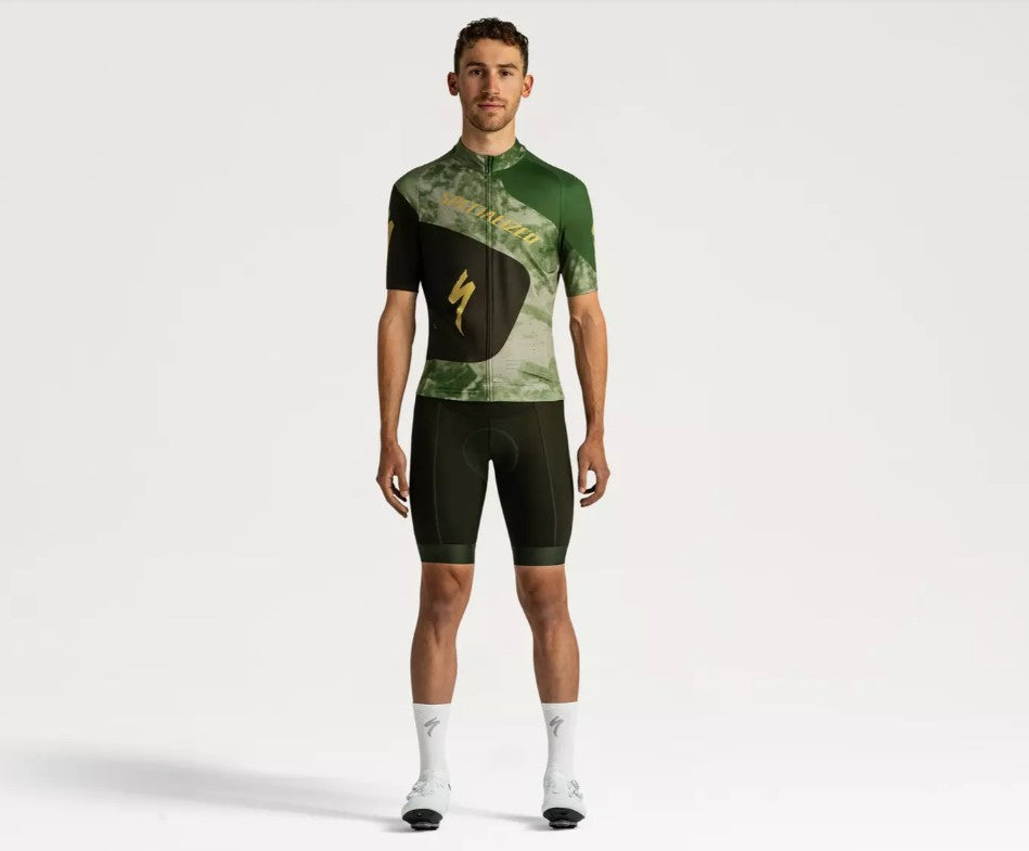 Front view of a man wearing a green and black Specialized Foundation short sleeve cycling jersey on a white background.
