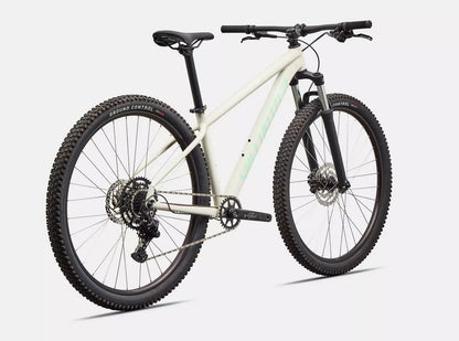 Back right angled view of white Specialized Rockhopper Sport mountain bike with black tires on a white background