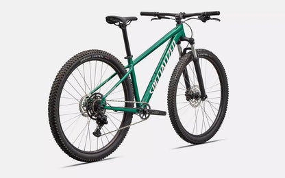 Rear right profile view of green Specialized Rockhopper Sport mountain bike with pink accents on a white background.