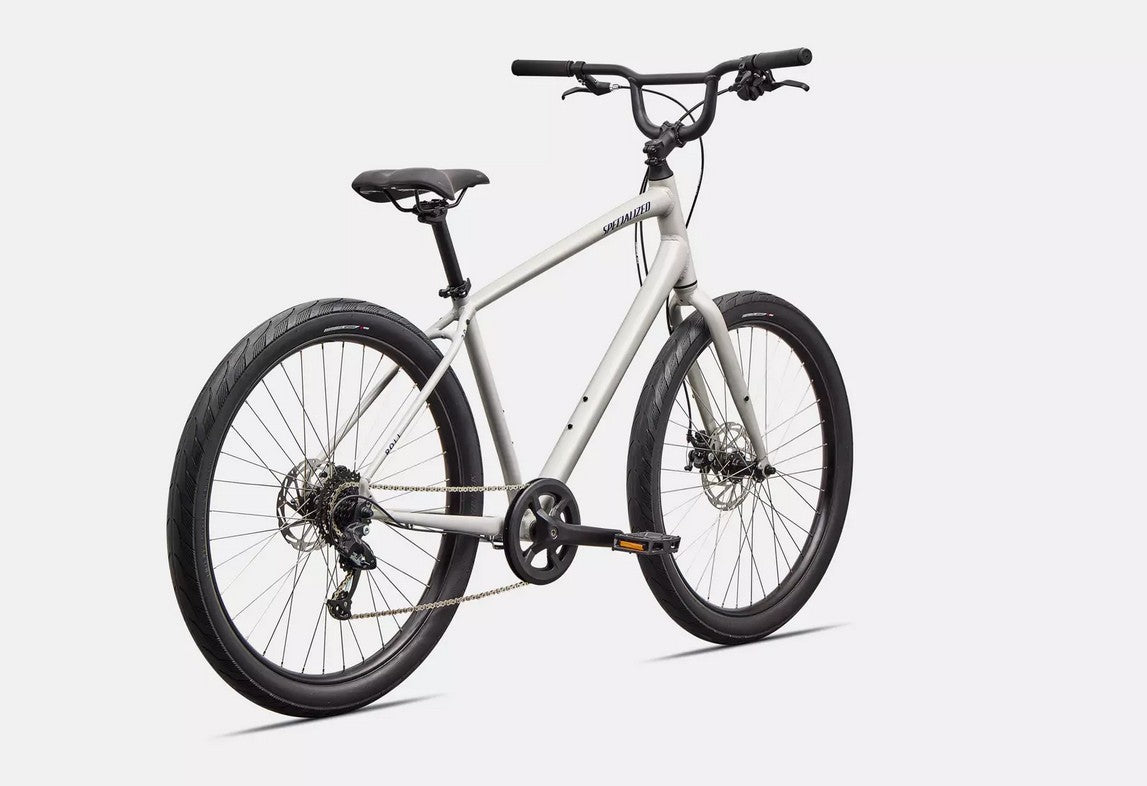 Rear right profile view of a white Specialized Roll bicycle with blue lettering and black components on white background. 