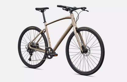 Front right profile of beige Specialized Sirrus bicycle with black components on white background.