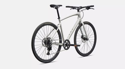 Back angled profile view of a white Specialized Sirrus X bicycle with black components on a white background. 