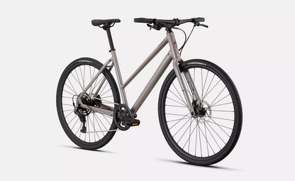 Front right angled profile view of a glass tan Specialized Sirrus bicycle with black components on a white background.