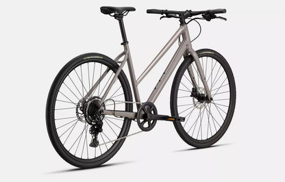 Back right angled profile view of a tan Specialized Sirrus X bicycle with black components on a white background. 