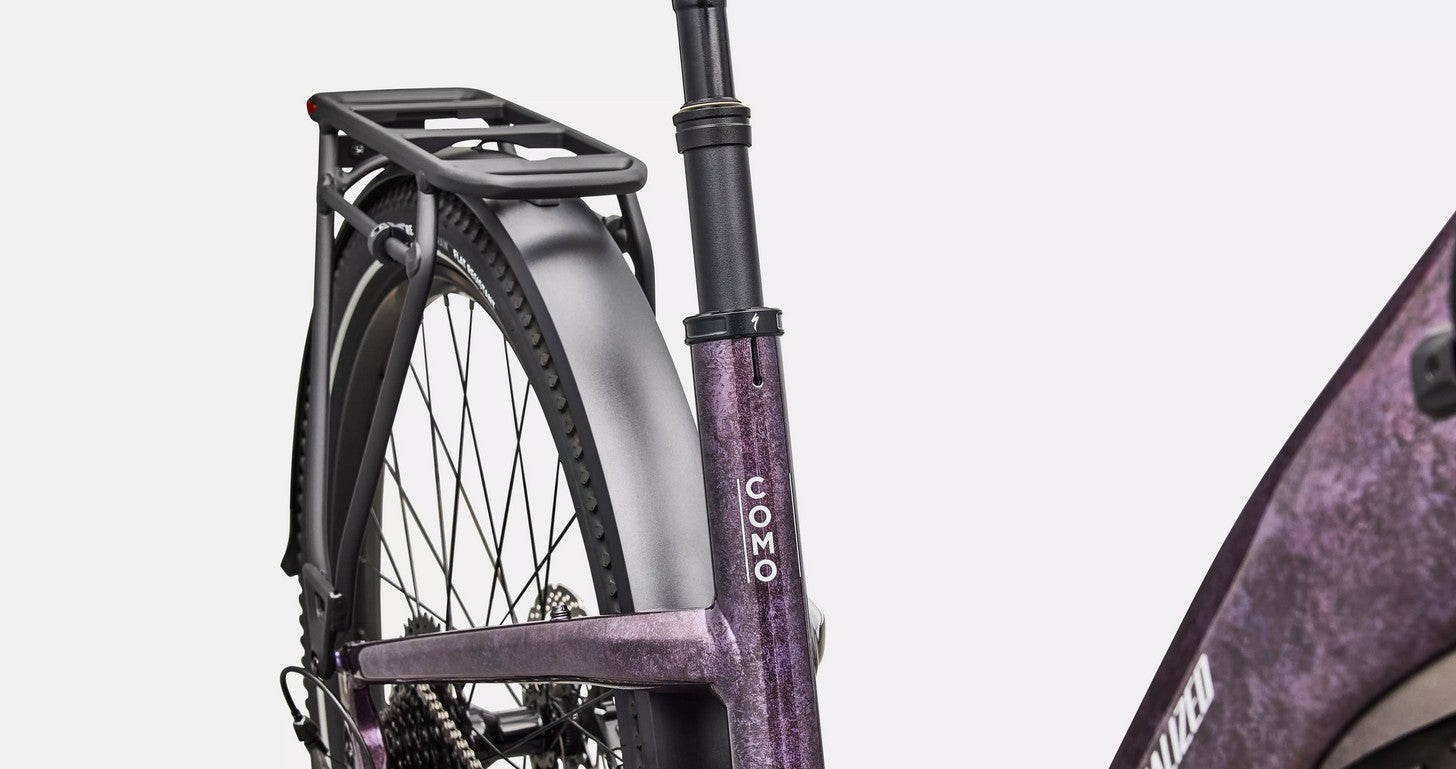 Close-up of a bicycle with a purple frame and black components on a light gray background.