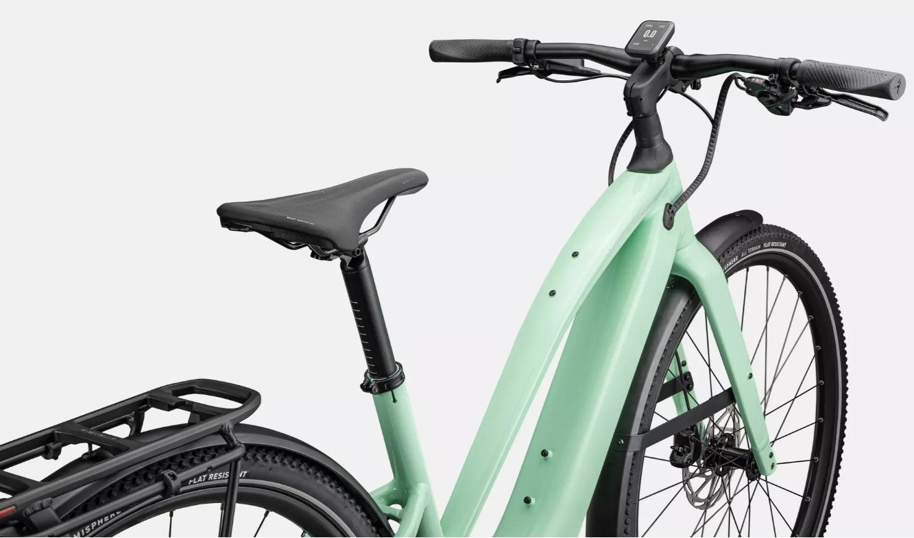 Close up view of light green Specialized Vado electric bicycle's saddle and handlebars, on a white background. 