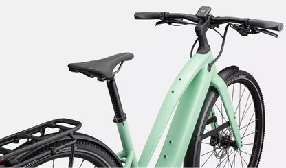 Close up view of light green Specialized Vado electric bicycle's saddle and handlebars, on a white background. 