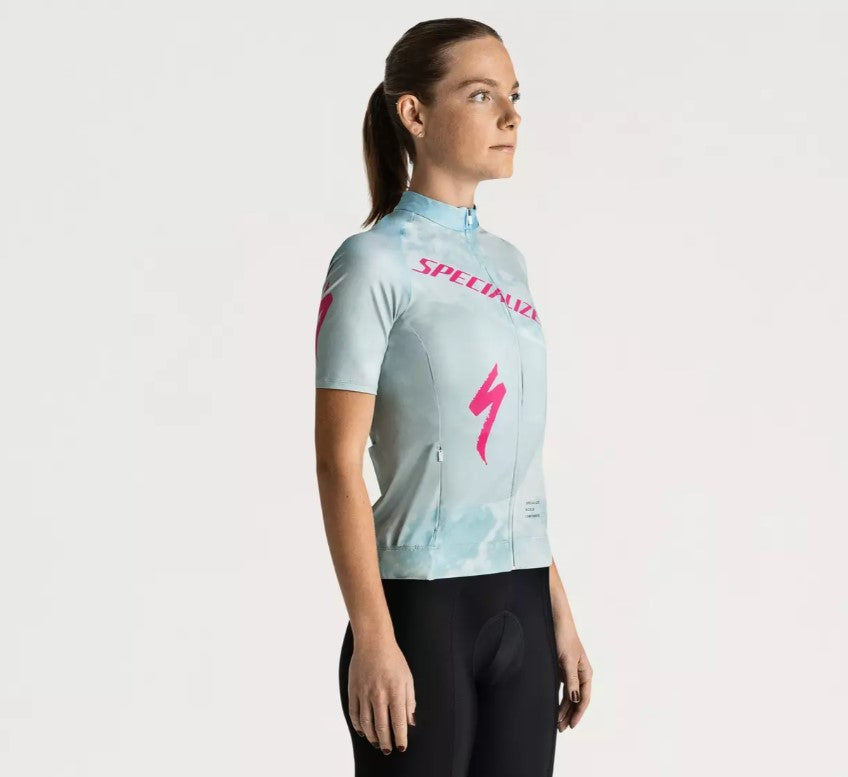 A right profile view of a person wearing a light blue Specialized Women's Foundation cycling jersey with pink Specialized logo on a white background.