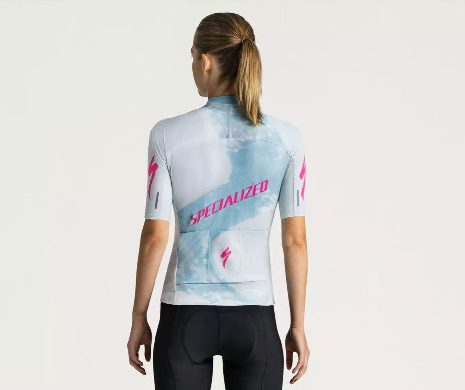A back view of a person wearing a light blue Specialized Women's Foundation cycling jersey with pink Specialized logo on a white background