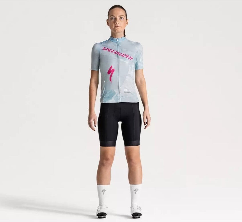 Person facing forward wearing a light blue Specialized Women's Foundation cycling jersey with pink Specialized logo on a white background