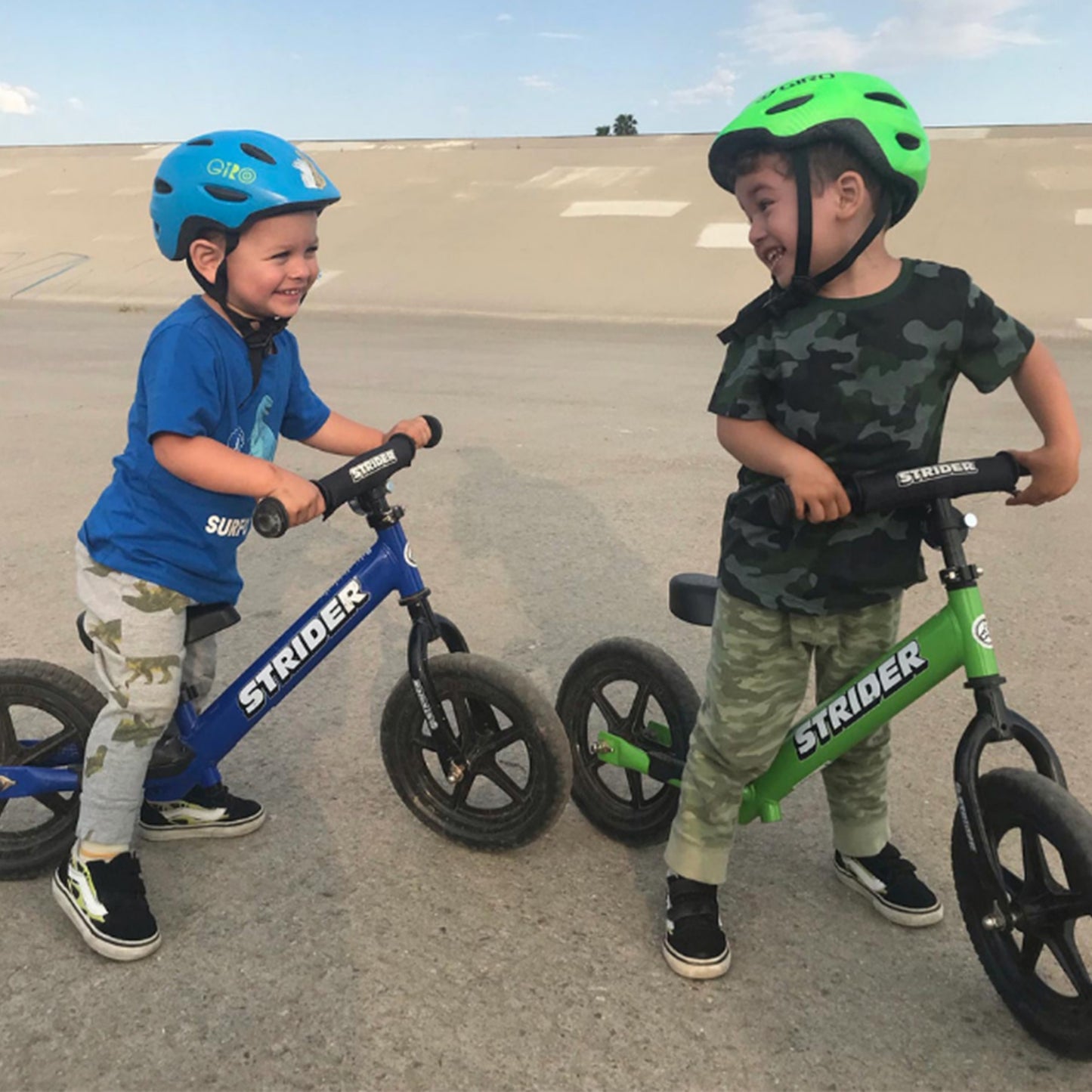 Two children on balance bikes with helmets in an outdoor setting