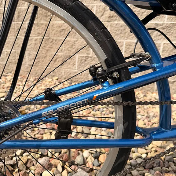 Closeup view of the rear brake and logo on the Sun Seeker Used EZ-Sport CX 26-20 Lemans Blue Recumbent Bike in an outdoor setting.