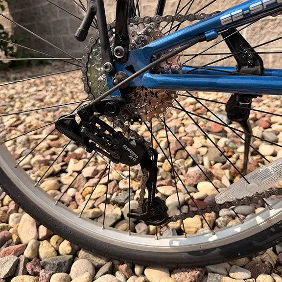 Closeup view of the cassette and rear derailleur on the Sun Seeker Used EZ-Sport CX 26-20 Lemans Blue Recumbent Bike in an outdoor setting.