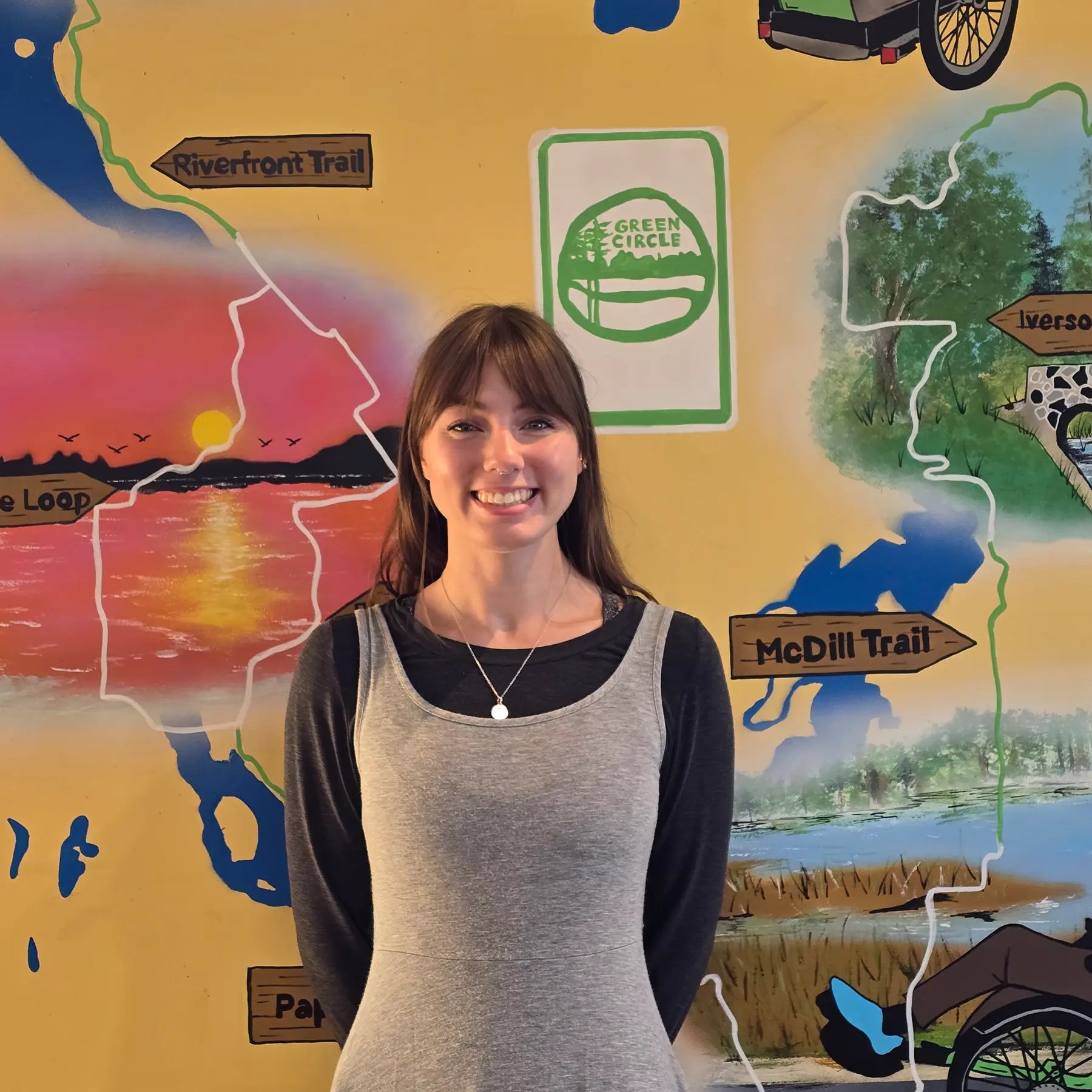 Sydney, Sales Staff member, in front of the Shoppe's Green Circle Mural, painted by KIBA Freeman Art: Muralist.