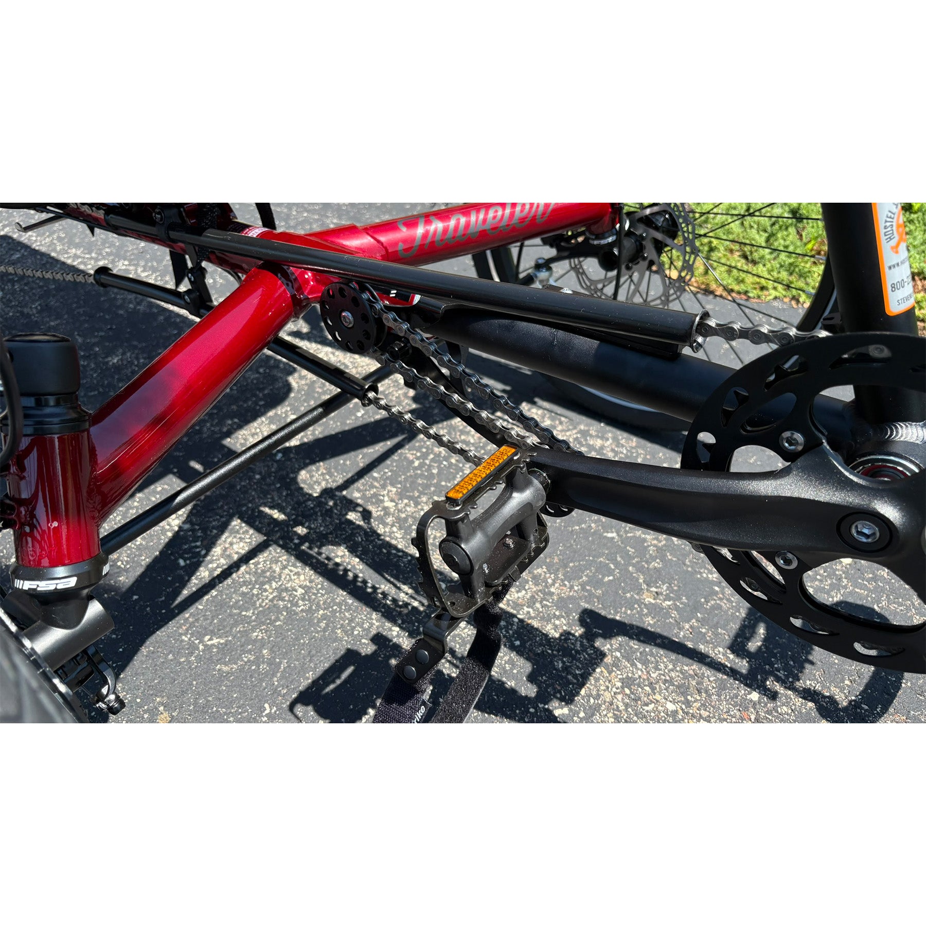 Close-up of a red bicycle frame with visible branding on a road.