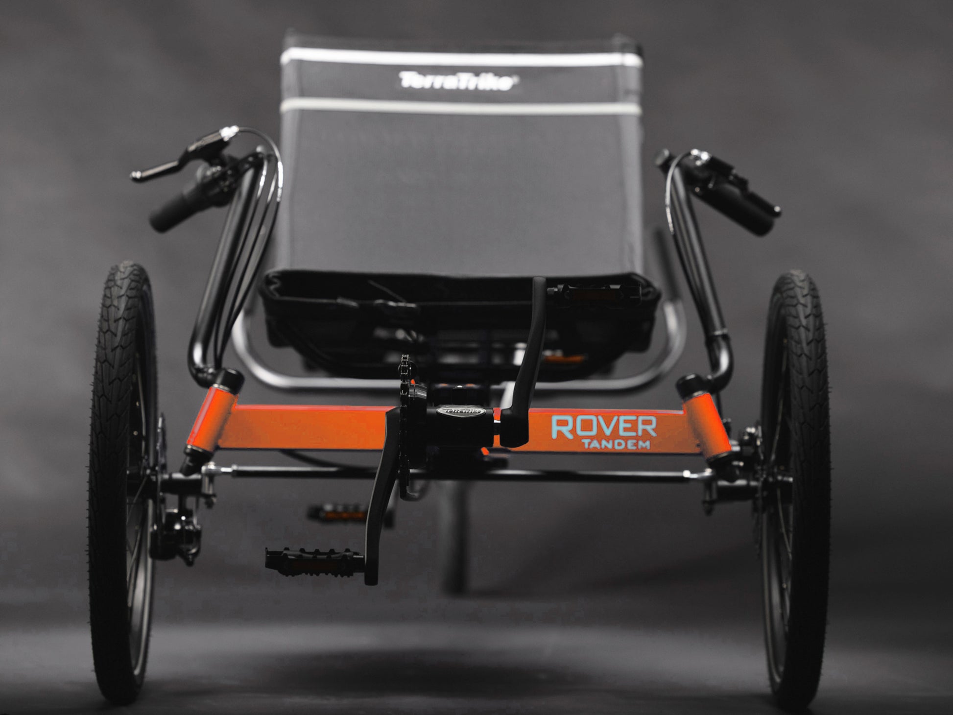 Front view of the TerraTrike Rover Tandem Recumbent Trike in Habanero Orange against a grey background.