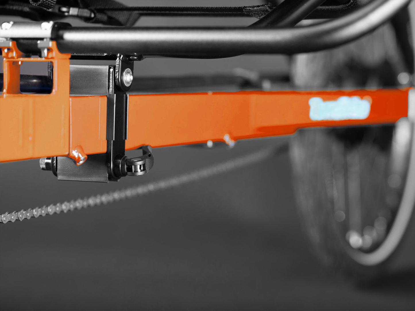 Closeup view of the seat adjustment and the frame splitter on the TerraTrike Rover Tandem Recumbent Trike in Habanero Orange against a grey background.