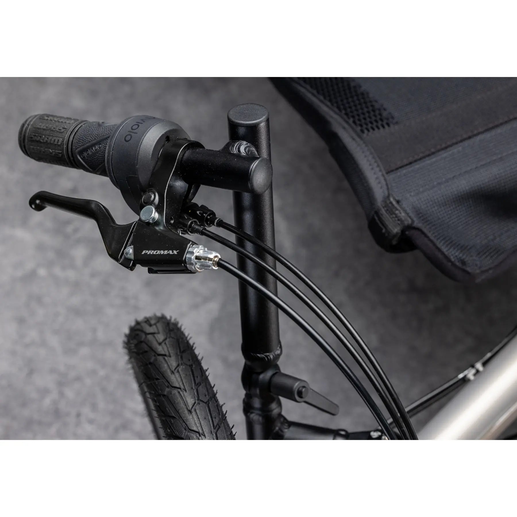 Closeup view of the handlebar, shifter and brake on the TerraTrike Traveler Champagne Recumbent Trike against a gray background.