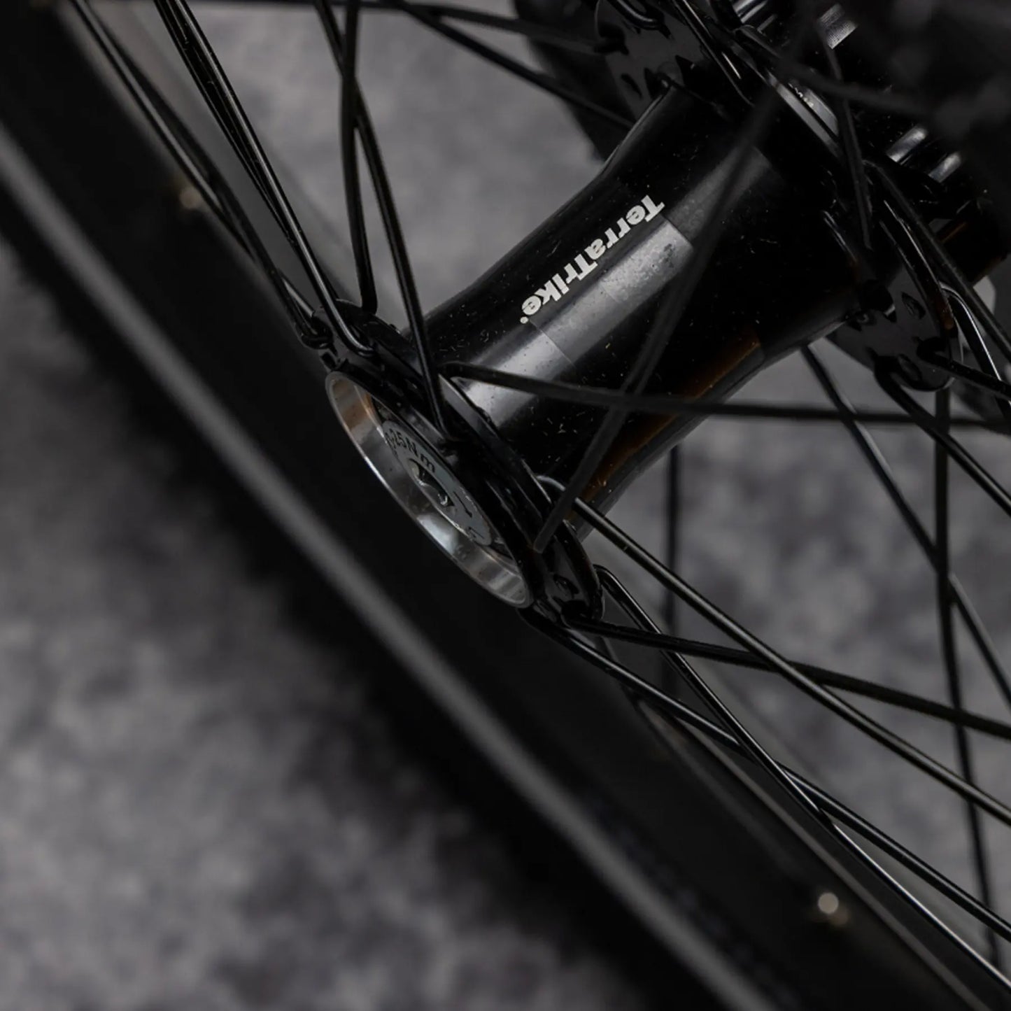 Closeup view of the TerraTrike front hub on the TerraTrike Traveler Champagne Recumbent Trike against a gray background.