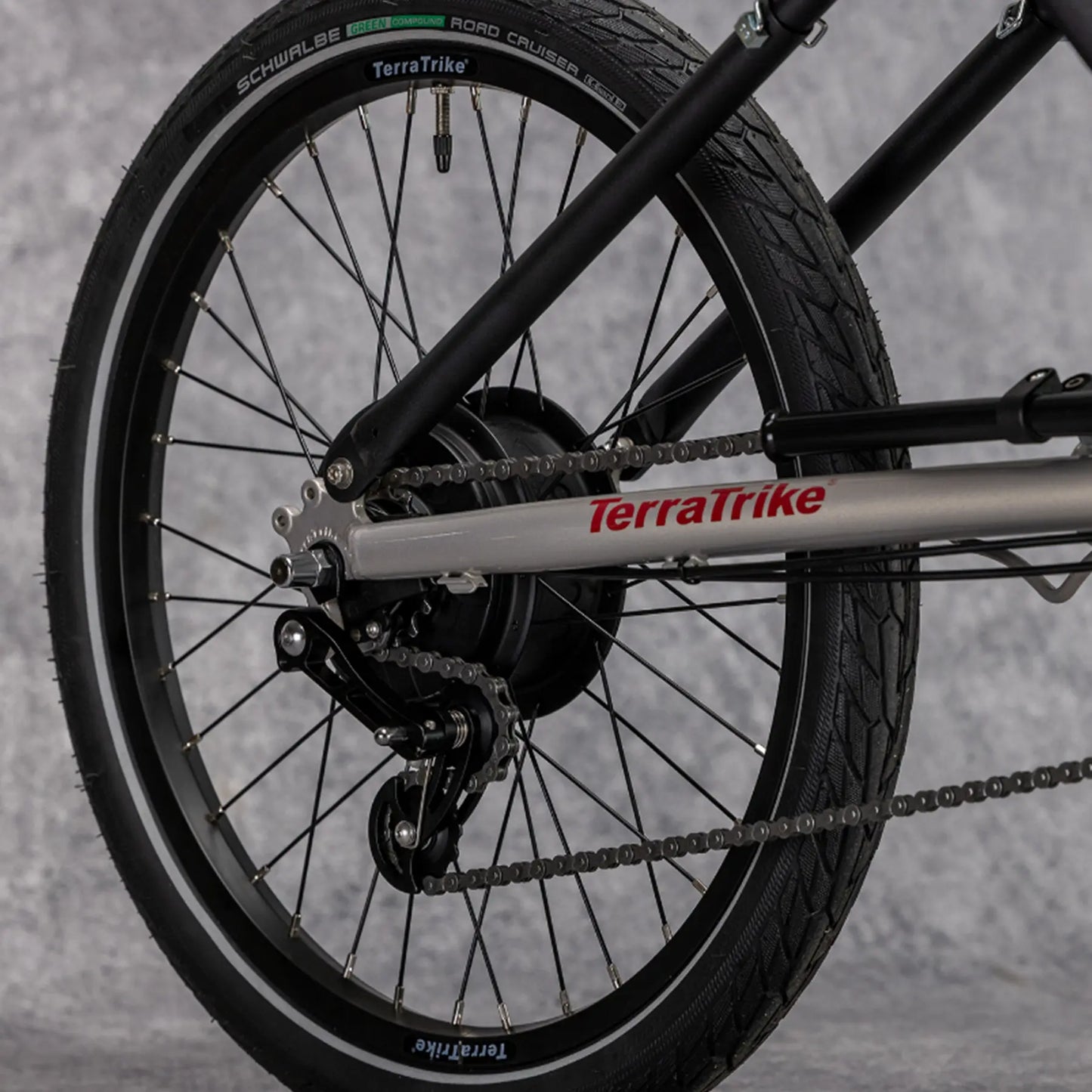 Closeup view of the Enviolo hub and rear wheel on the TerraTrike Traveler Champagne Recumbent Trike against a gray background.
