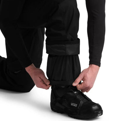View of inner cuff by the ankle on The North Face Mens Freedom Insulated Black Pant on a kneeling model against a white background.