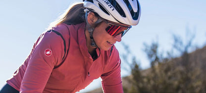 Person with a white helmet, pink long sleeve top and Tifosi Moab Lite Matte Bronze sunglass with red fototec lens.