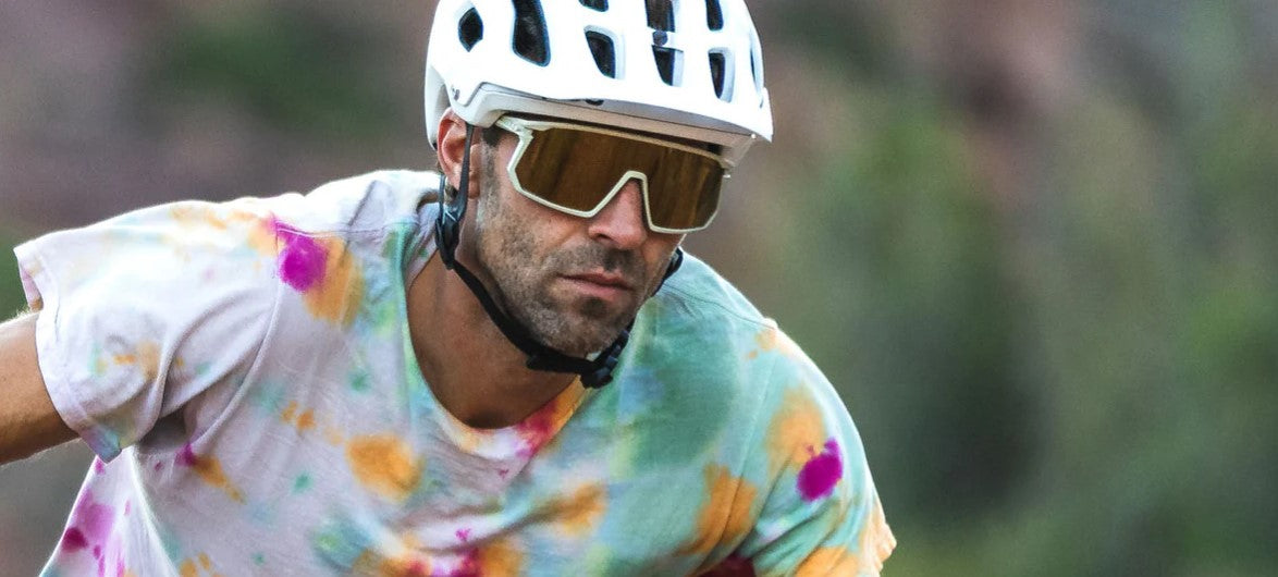 Person wearing a helmet and colorful shirt with off-white Tifosi Moab sunglasses, riding a bike.