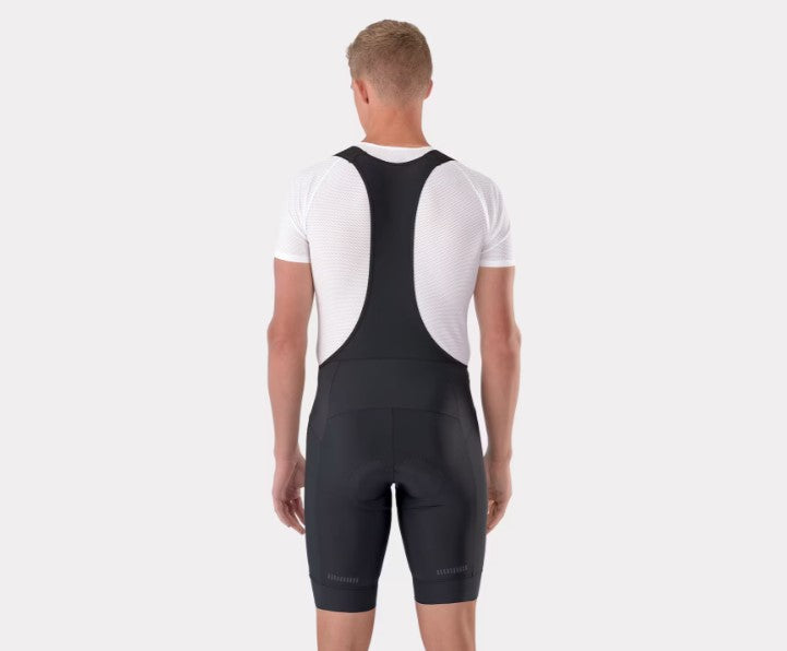 Back view of person wearing black Trek Circuit cycling bib shorts with white shirt underneath. 