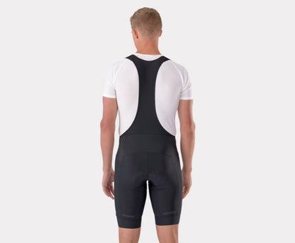 Back view of person wearing black Trek Circuit cycling bib shorts with white shirt underneath. 