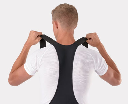 Top shoulder view of person wearing black Trek circuit bib shorts, pulling up on the straps. 