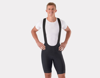 Man wearing a black Trek Circuit cycling bib shorts and white shirt on a light gray background