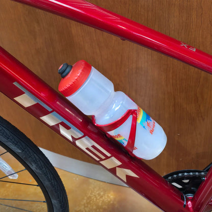 Side view of the Trek Elite Recycled Water Bottle Cage in Crimson-Dark Red on a red Trek bike with a Hostel Shoppe water bottle in the cage.