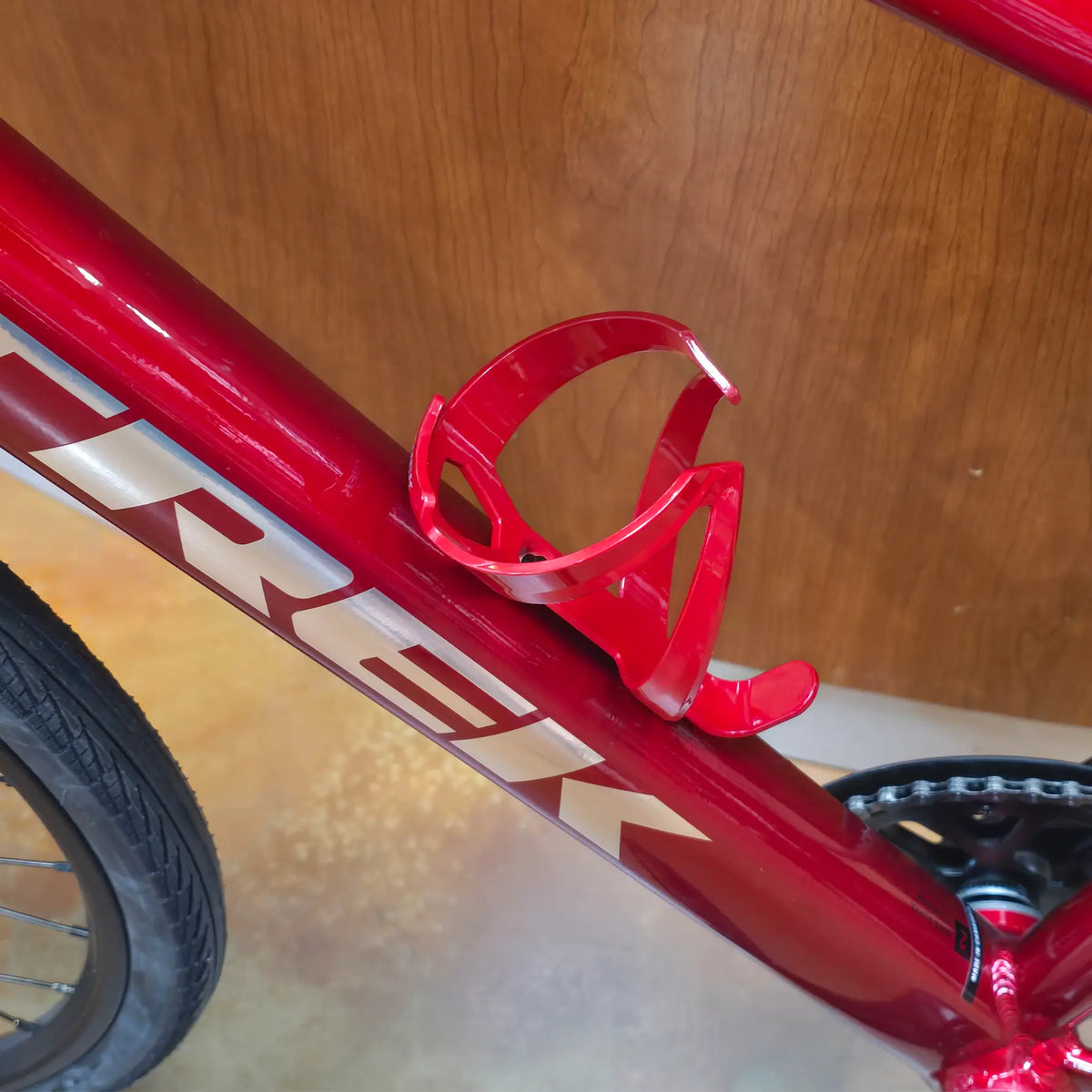 Side view of the Trek Elite Recycled Water Bottle Cage in Crimson-Dark Red on a red Trek bike.