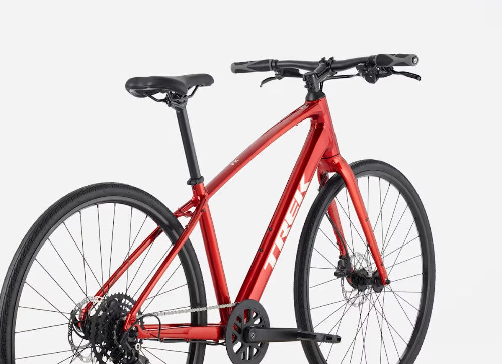 Back right profile view of a red Trek FX bicycle with white lettering and black components on a white background. 