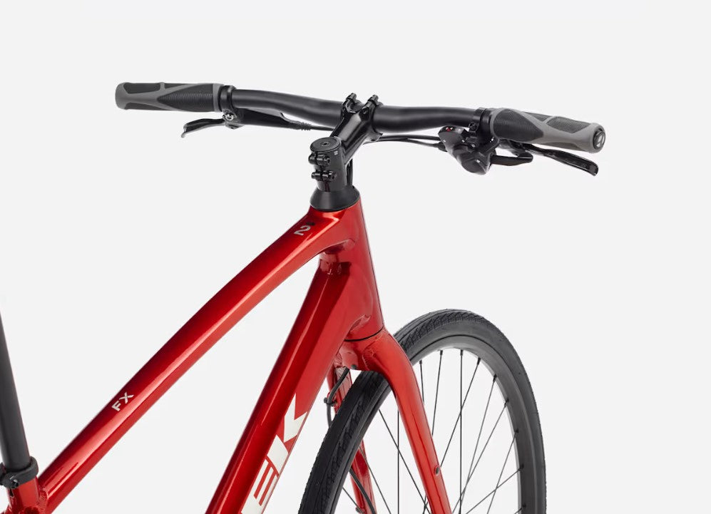 Handlebars and front wheel of a red Trek FX bicycle on a white background. 