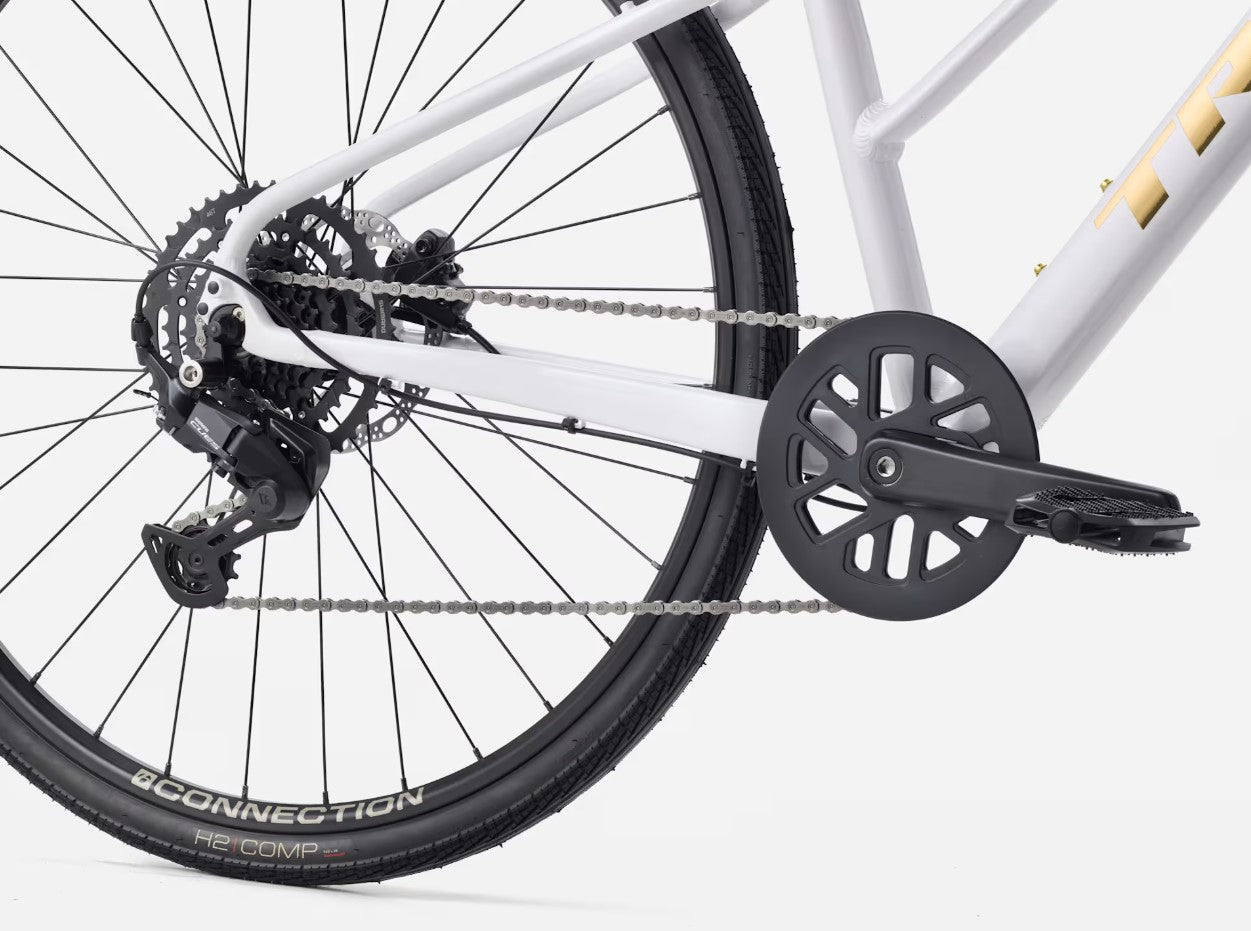 Close-up of a white Trek FX 2 bicycle's rear wheel and gear system on a white background.